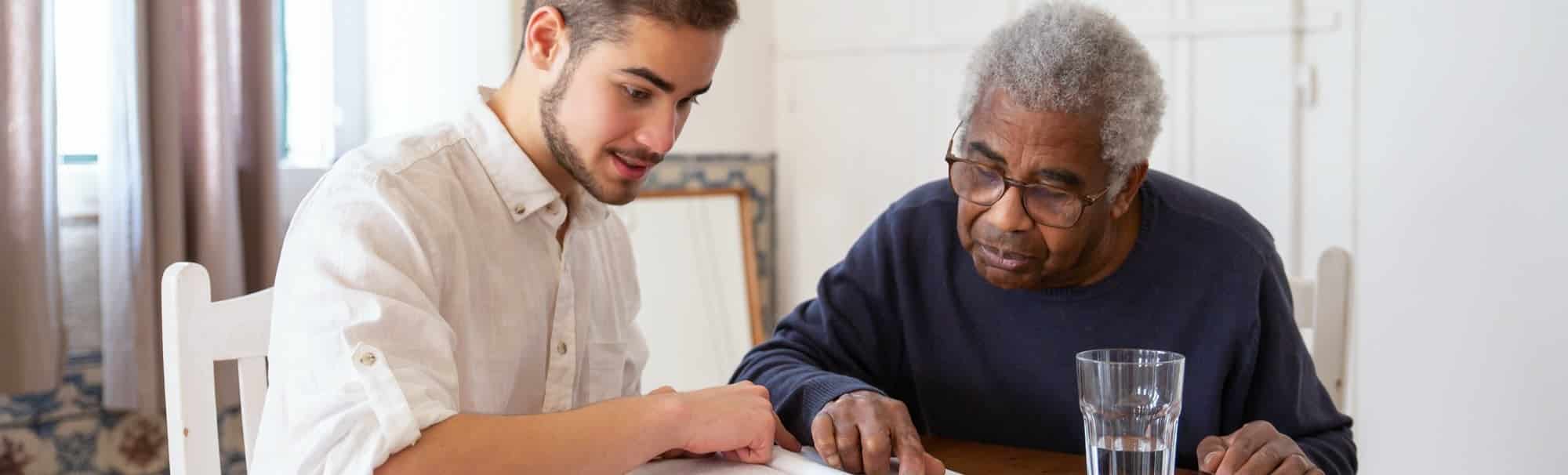 Elderly person recieving assistance with reading