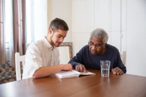 Elderly person recieving assistance with reading